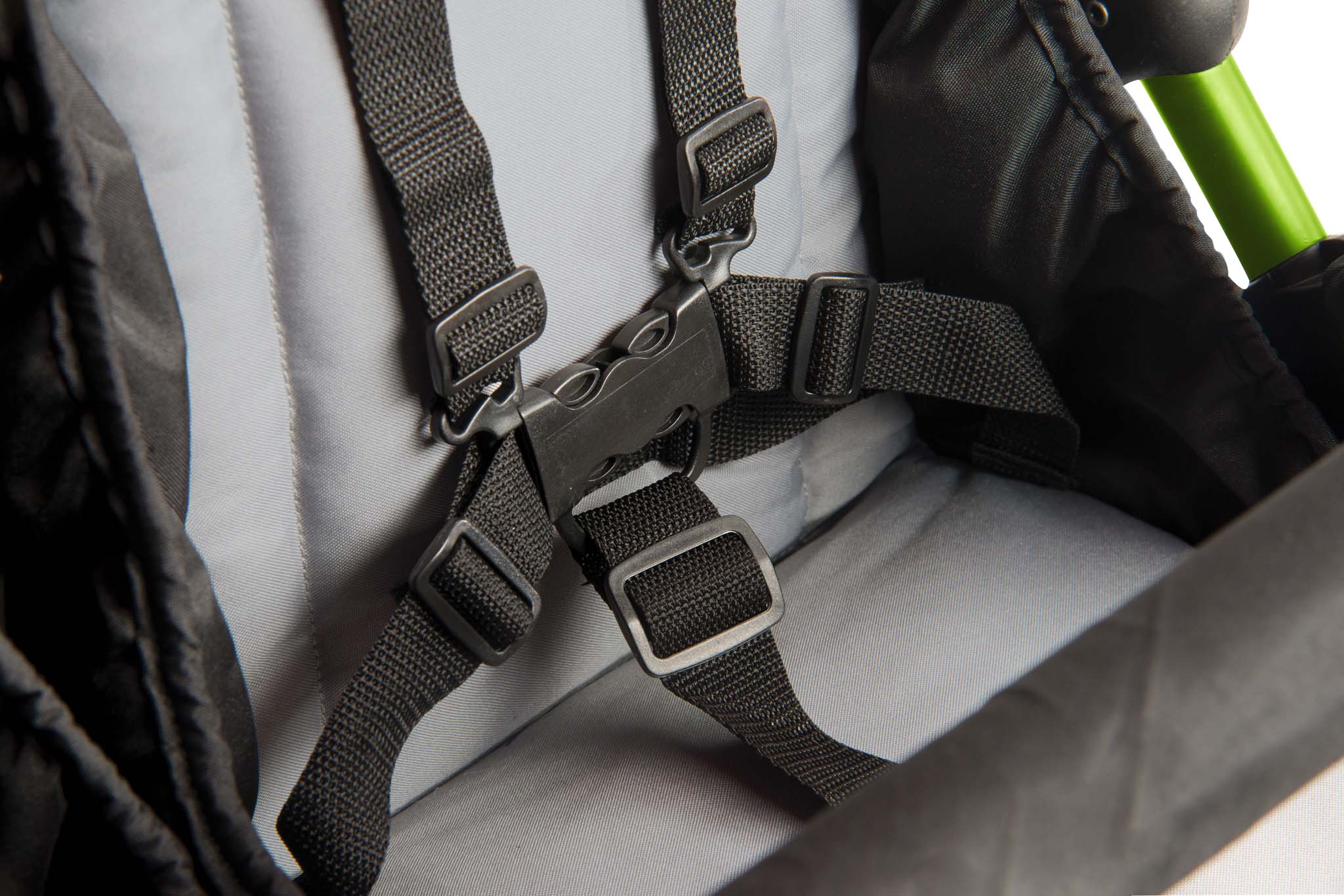 Close-up of a child safety seat harness with a green handle.