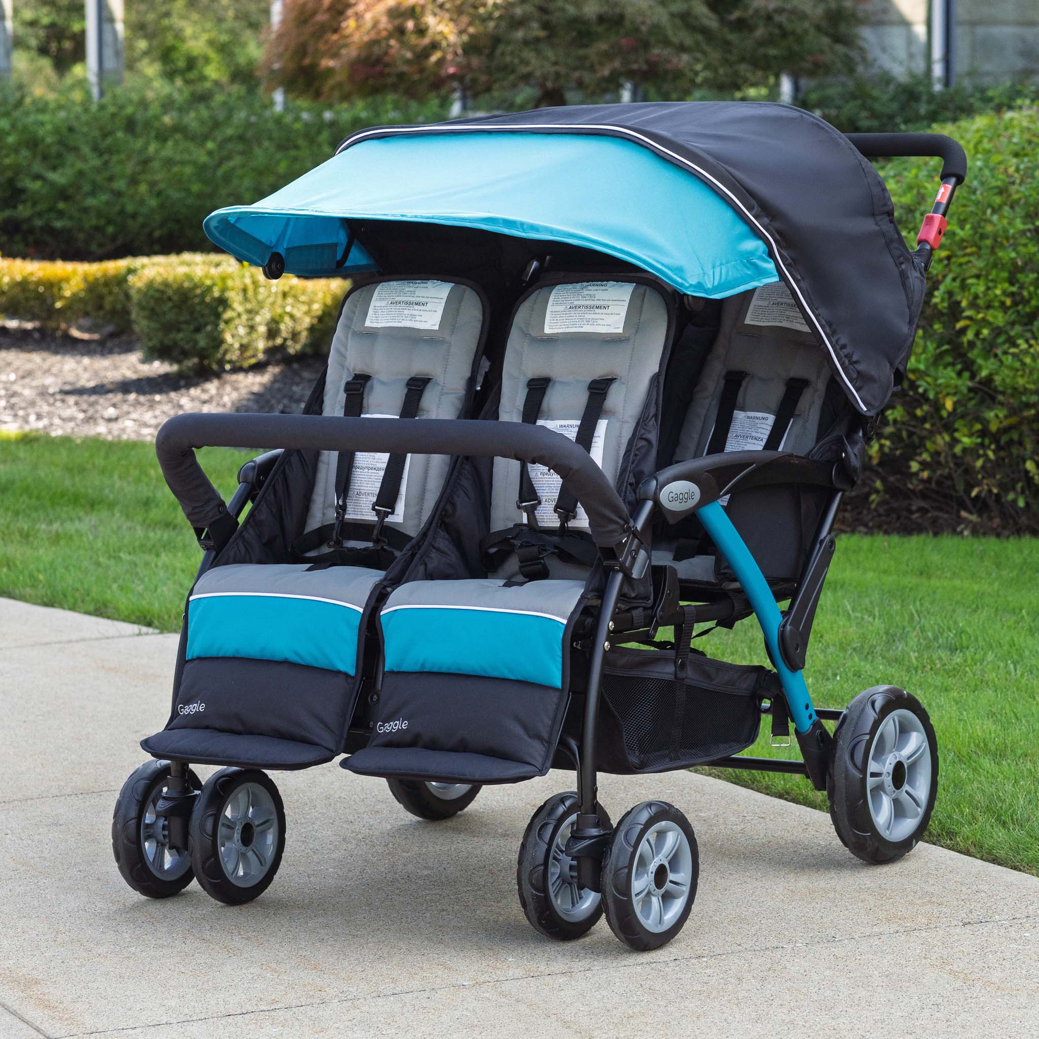 stroller with blue canopy and 4 seats on a sidewalk