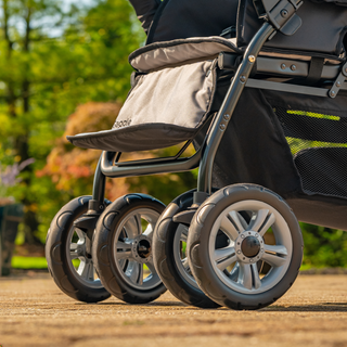 Close-up of a stroller wheels with visible brand name in an outdoor setting