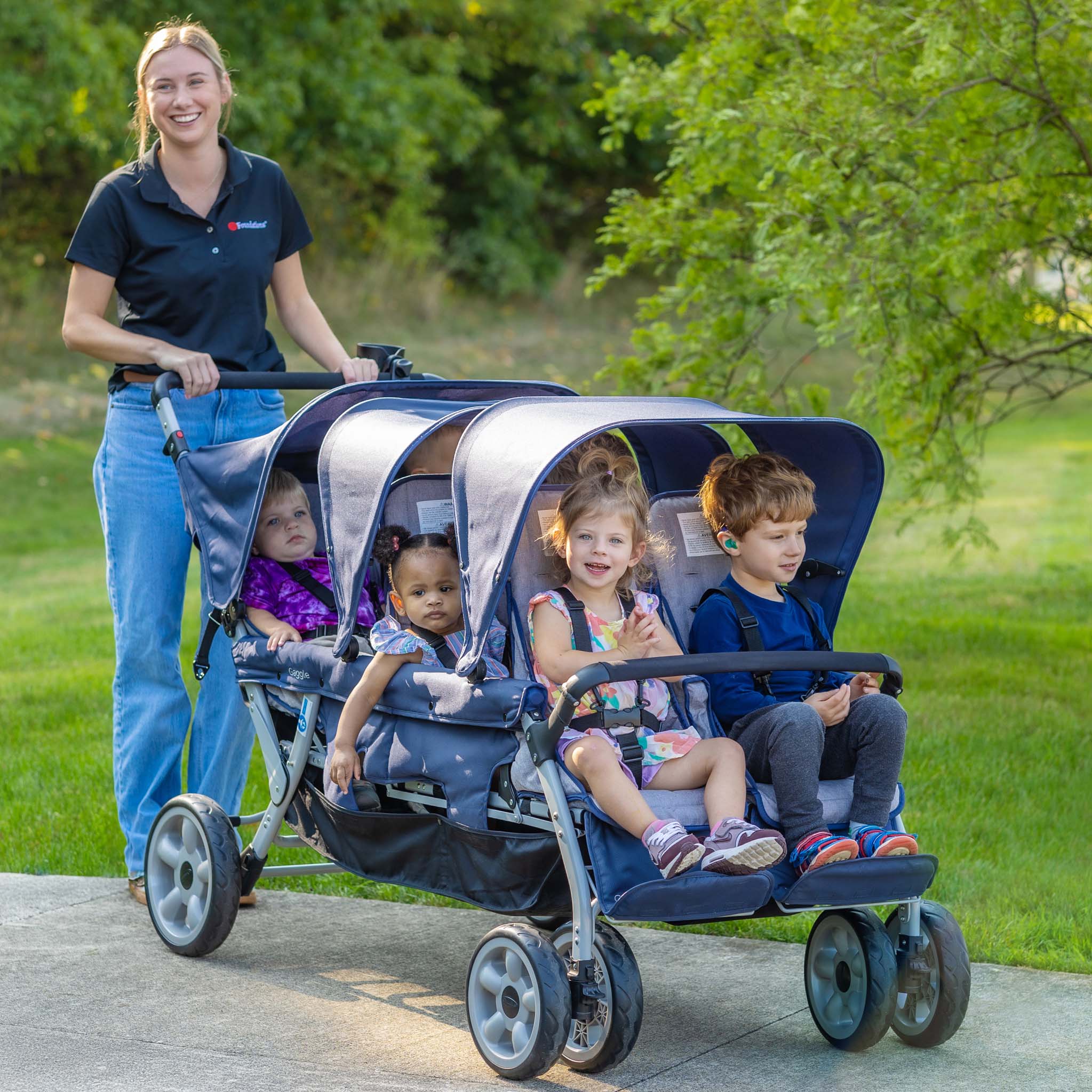 Woman pushing a stroller with six children in a park