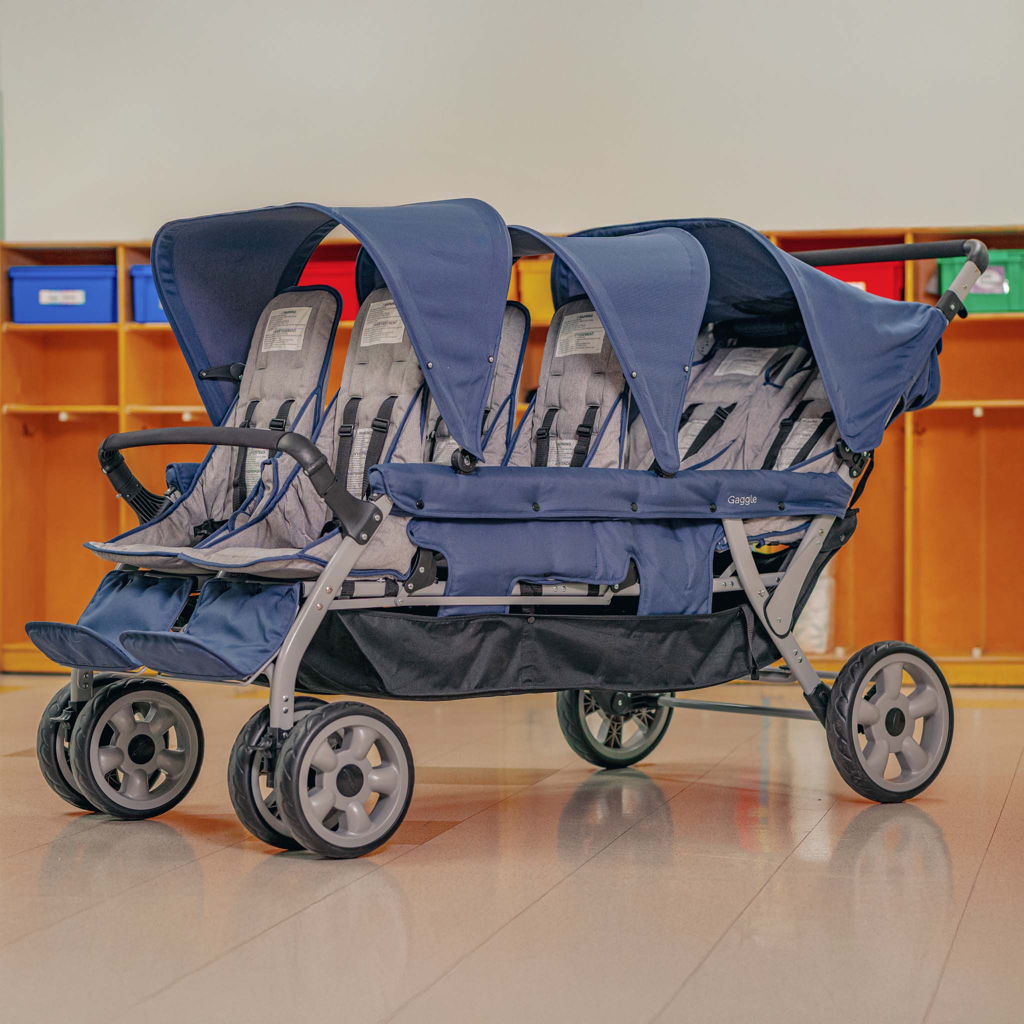 six seat stroller with blue canopies on a tiled floor.