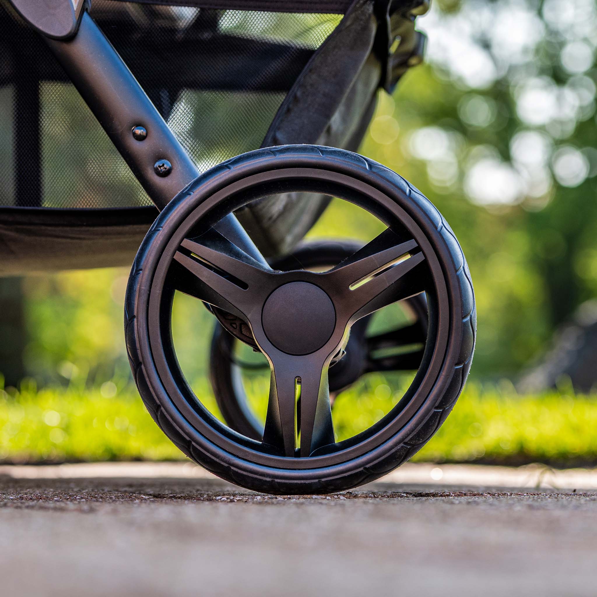 Close-up of a stroller wheel on a grassy outdoor background