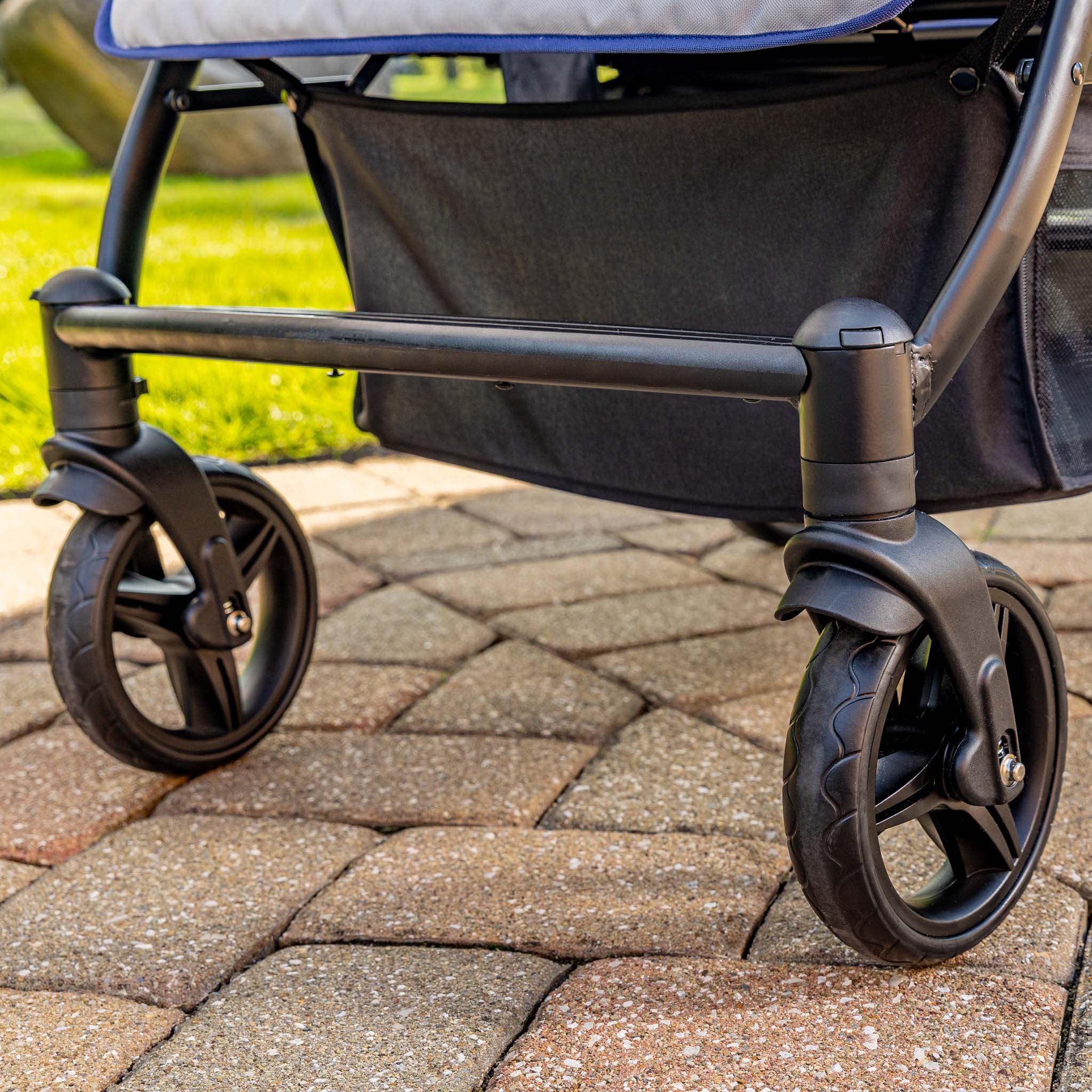 Close-up of a stroller's wheels on a paved surface with grass in the background
