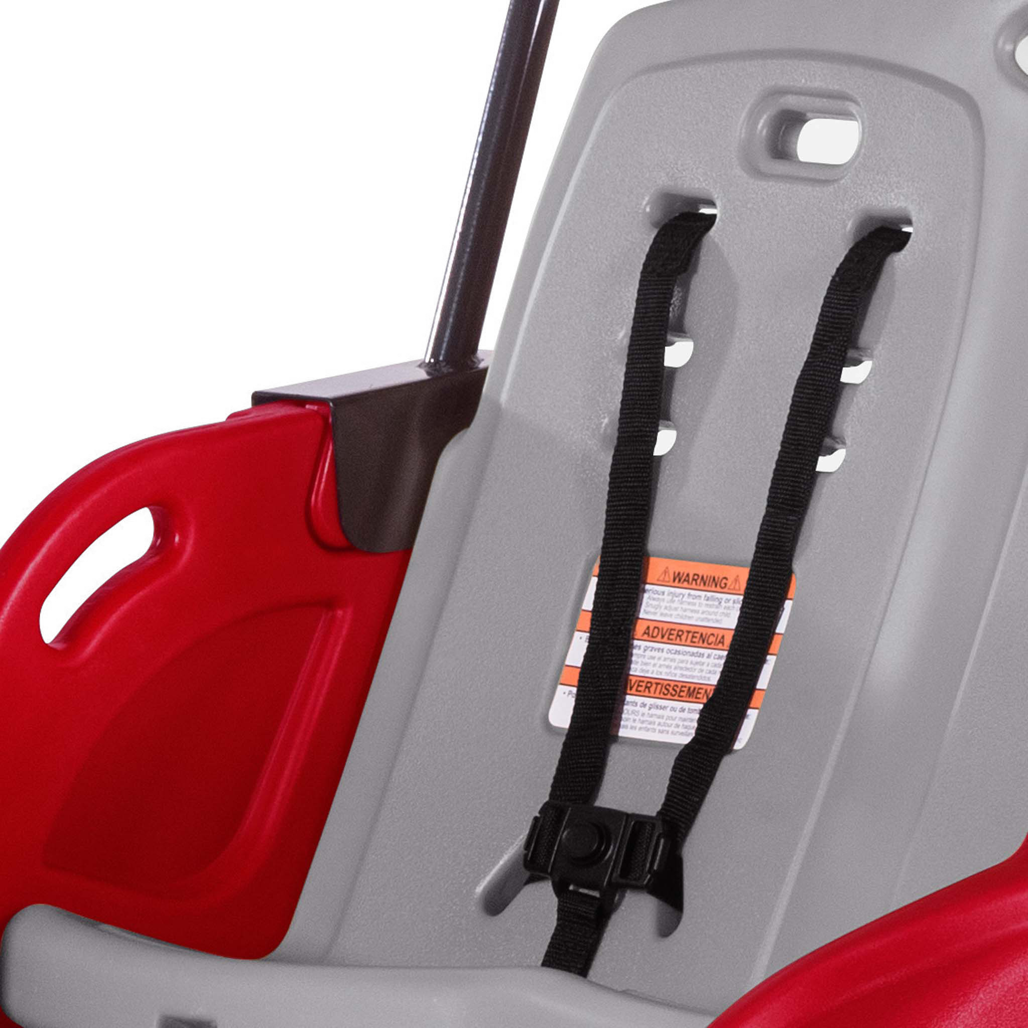 Close-up of a red and gray child safety seat with a black harness and warning label.