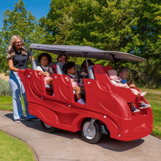 Red six seat buggy with children and an adult on a sunny day outdoors