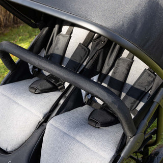 Close-up of a double stroller with gray seats and black armbar