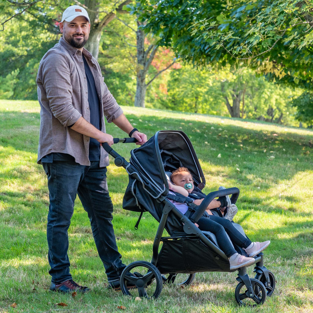Man pushing a double stroller with children in a park